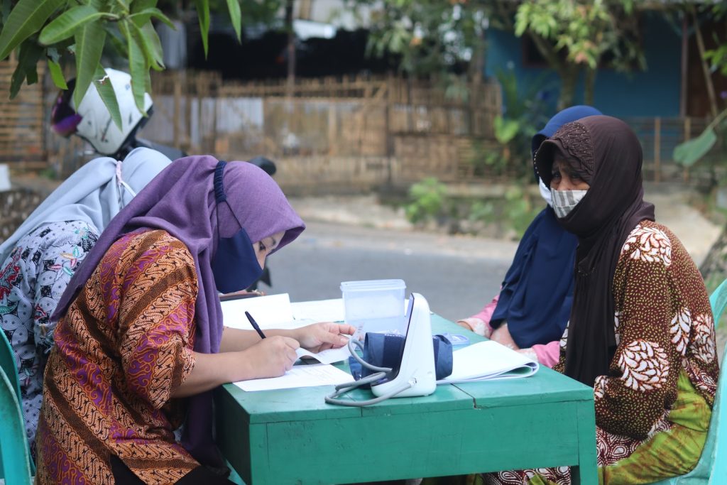 woman in brown and red hijab sitting on green box